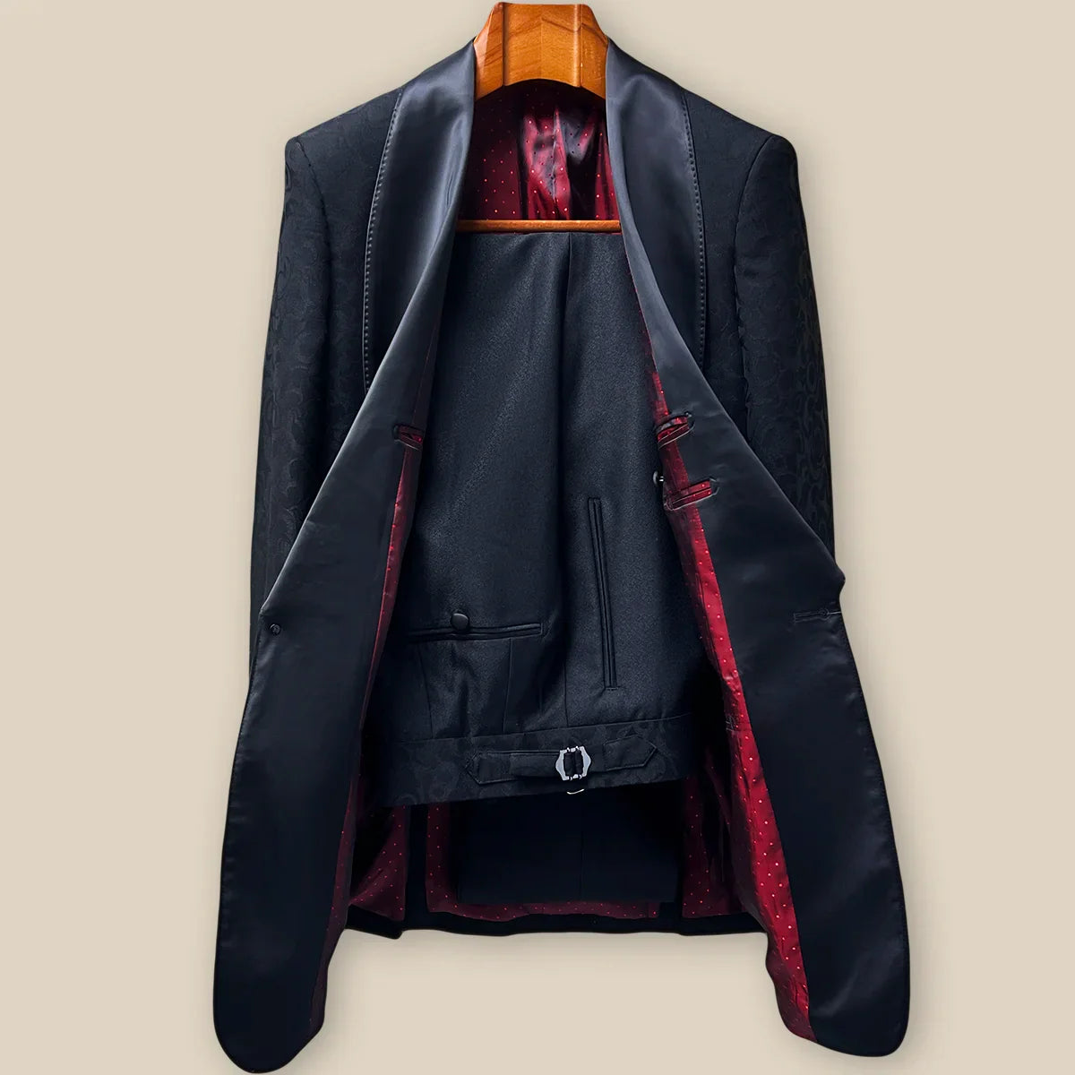 Complete two-piece black self floral tuxedo displayed on hanger showing jacket and trousers with subtle floral pattern