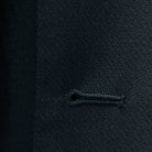 Macro view of precise buttonhole stitching on a black self-textured jacquard suit