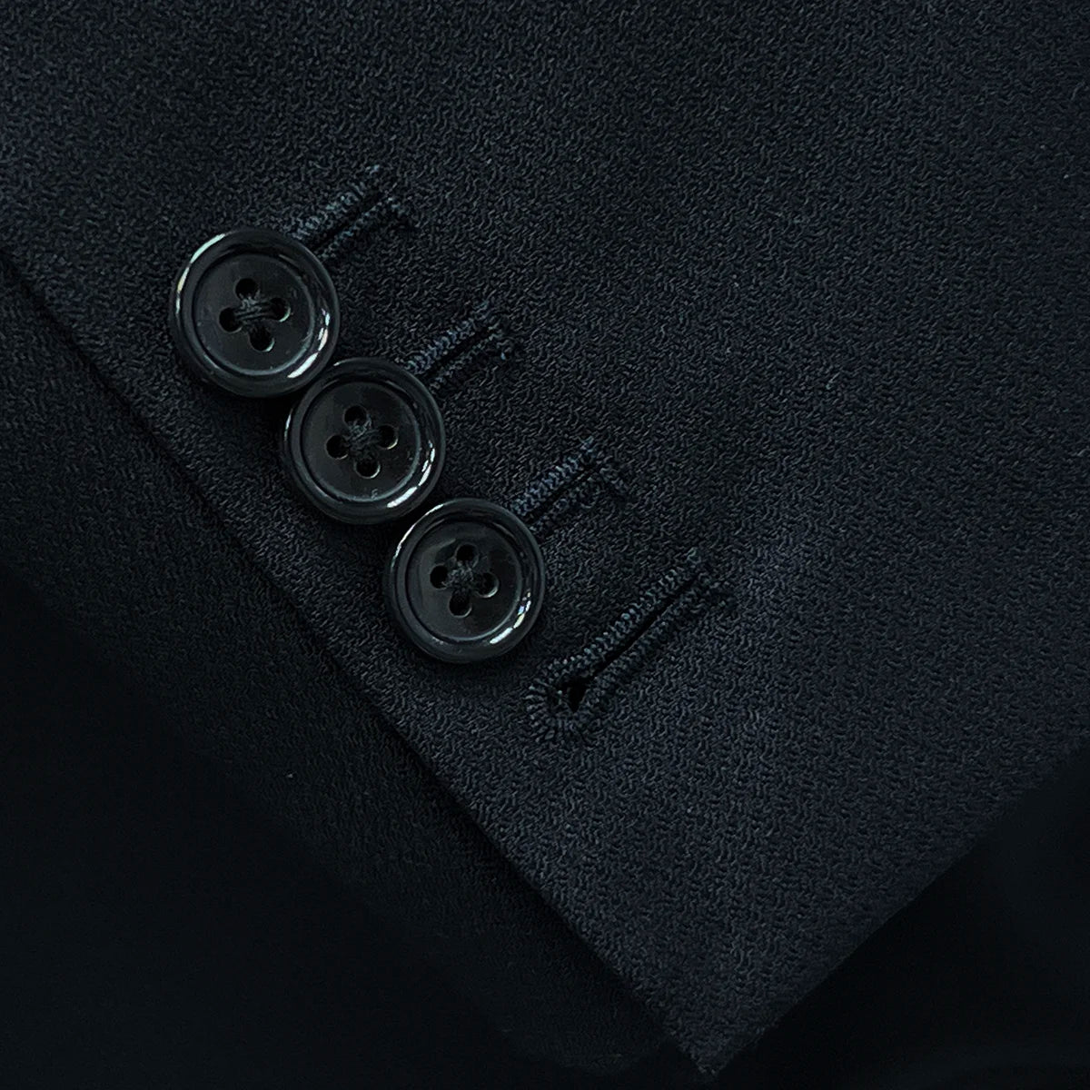 Detail shot of functional buttonholes on the sleeve of a black Westwood Hart suit jacket