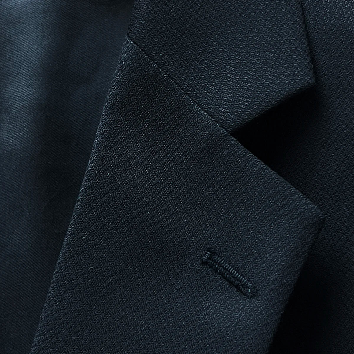 Detail view of the notch lapel on a black self-textured jacquard Westwood Hart suit jacket