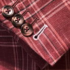 Sport coat sleeve cuff showing functional buttonholes with contrast white accent stitching on burgundy plaid fabric