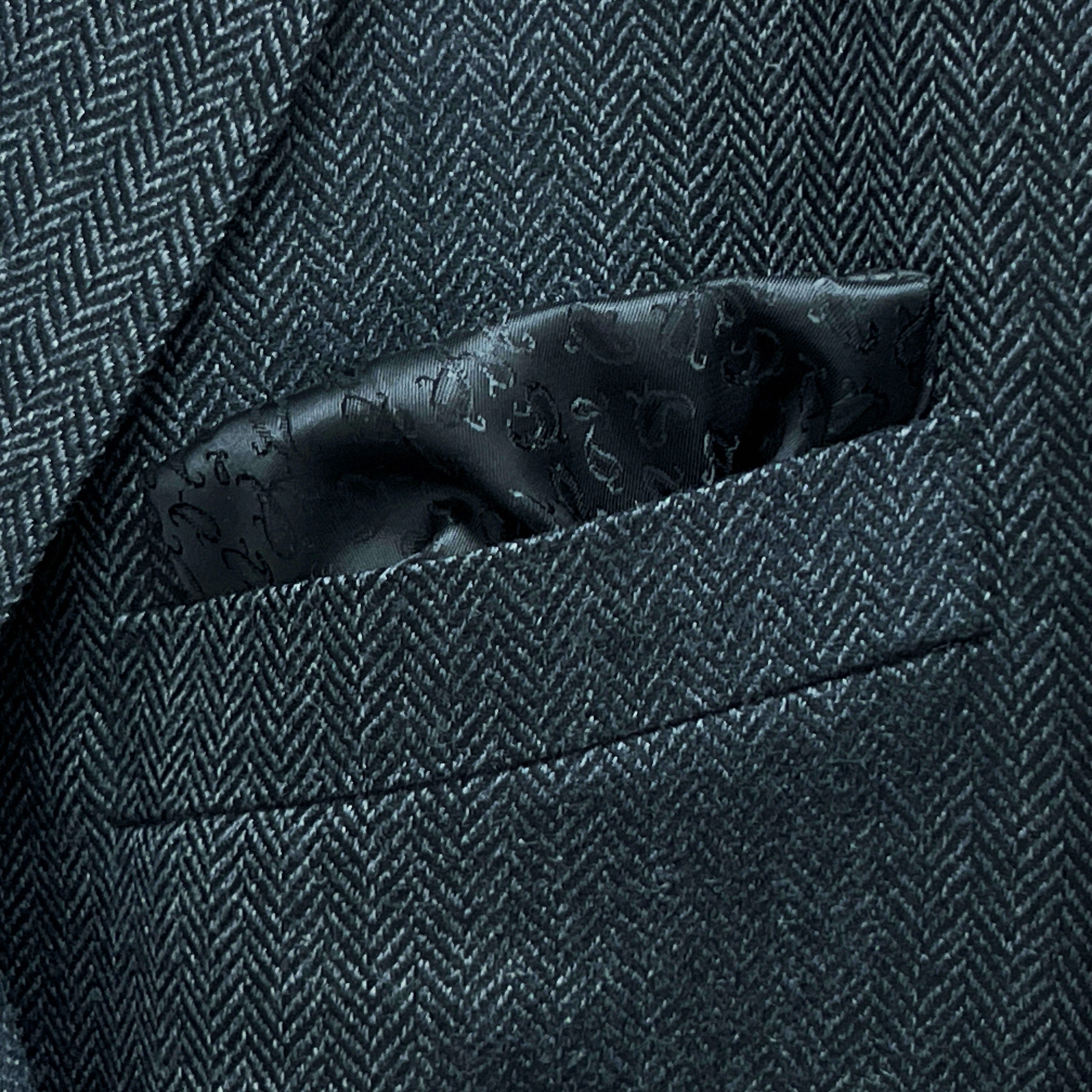Breast pocket of charcoal grey herringbone sport coat with built-in pocket square holder and hand-finished edges