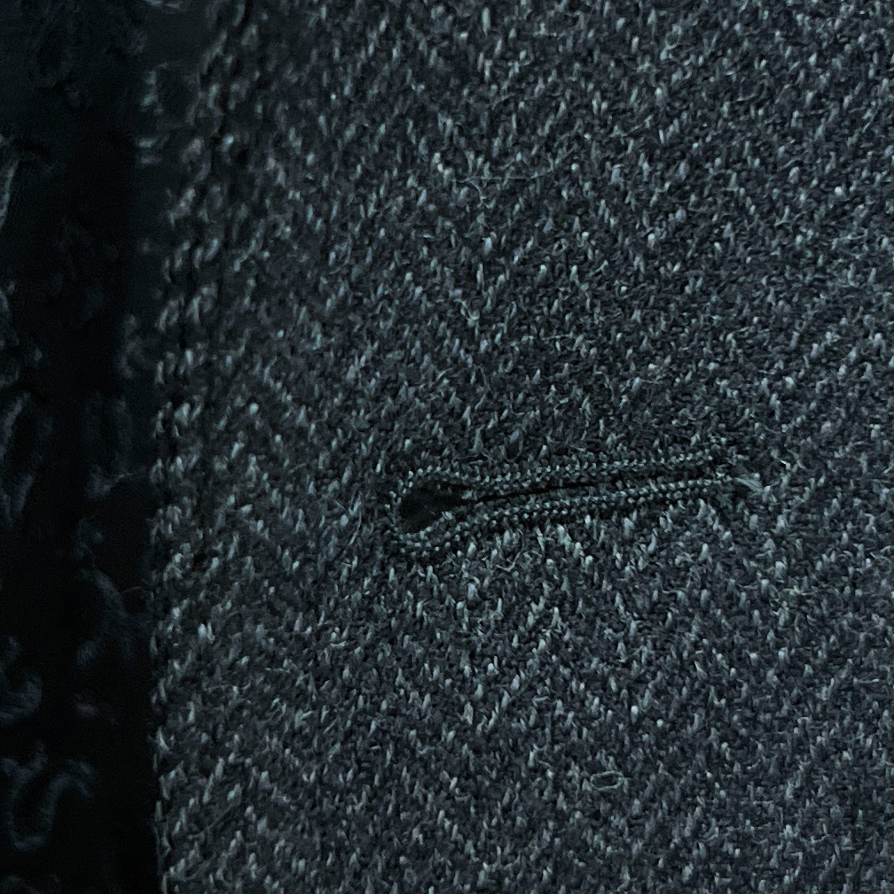 Detailed macro shot of hand-finished buttonhole stitching on charcoal grey herringbone sport coat with edge pick stitching