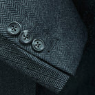 Sport coat sleeve cuff showing functional buttonholes with edge pick stitching on charcoal grey herringbone fabric