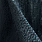 Close-up of charcoal grey herringbone tweed wool fabric showing distinctive diagonal weave pattern and texture