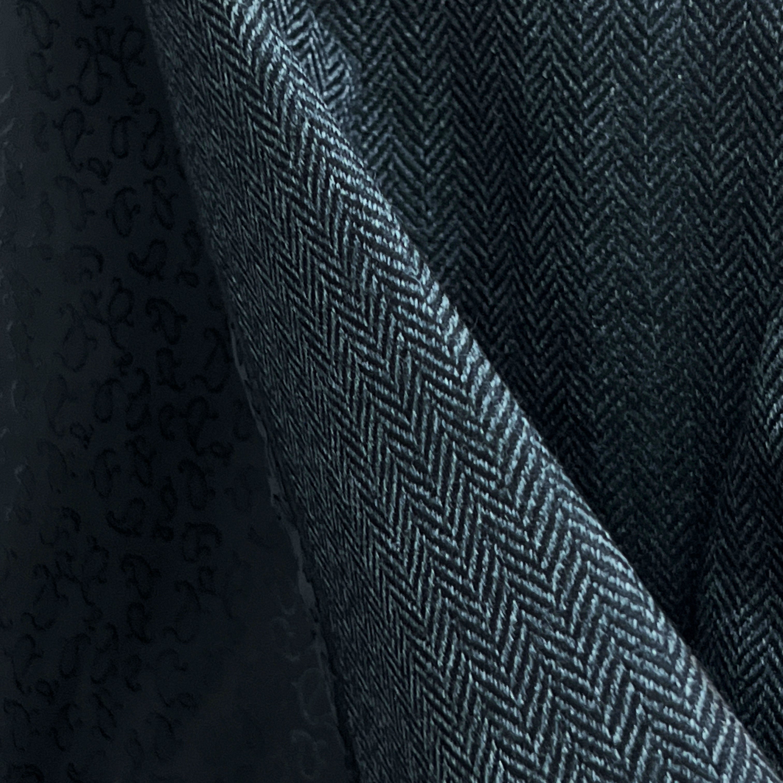 Close-up of charcoal grey herringbone tweed wool fabric showing distinctive diagonal weave pattern and texture