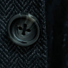 Close-up of charcoal horn buttons with light grey marbling on charcoal grey herringbone sport coat showing natural patterns