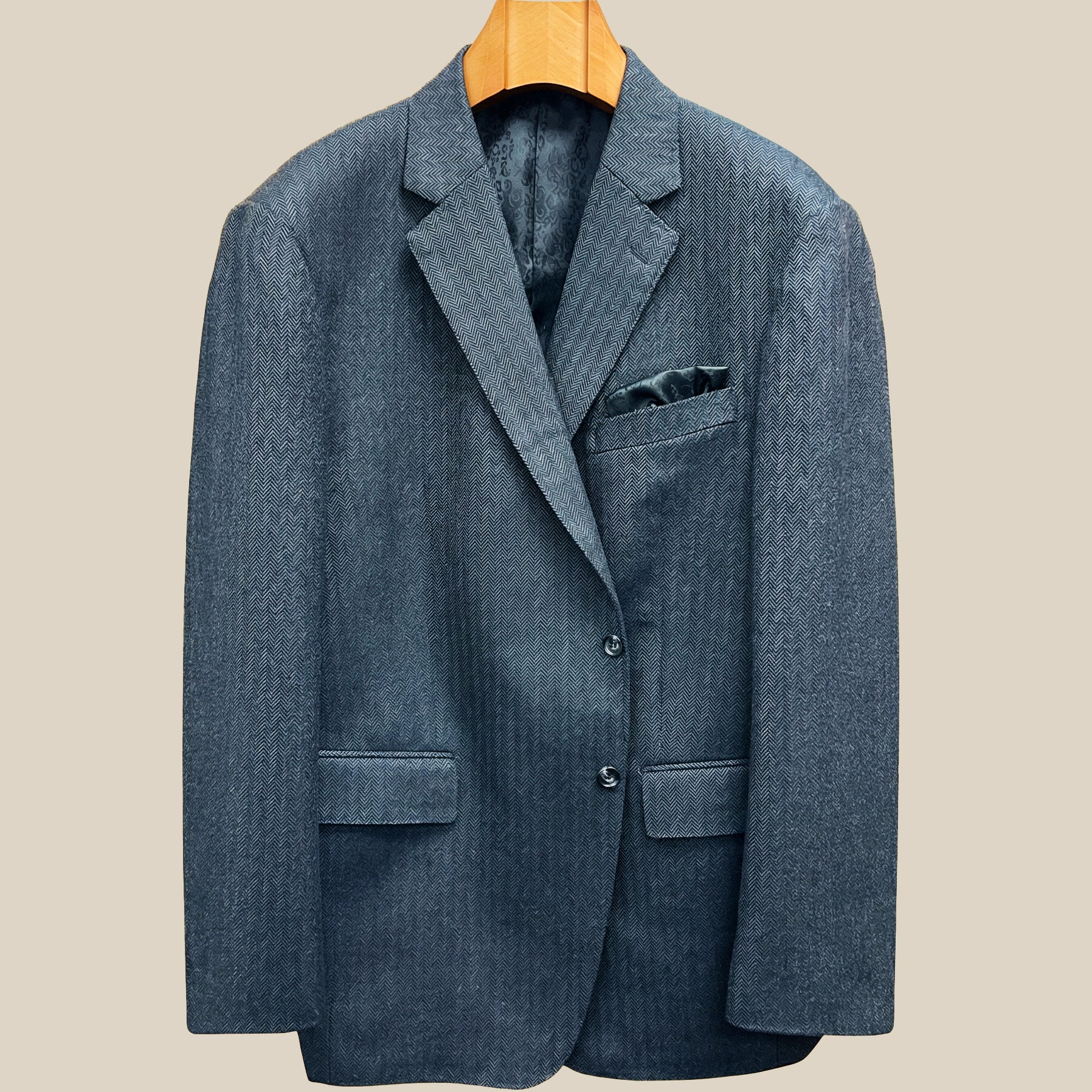 Front button panel of charcoal grey herringbone sport coat featuring charcoal horn buttons with light grey marbling and hand pick stitching