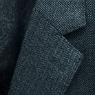 Classic notch lapel detail on charcoal grey herringbone sport coat showing hand pick stitching and herringbone weave pattern