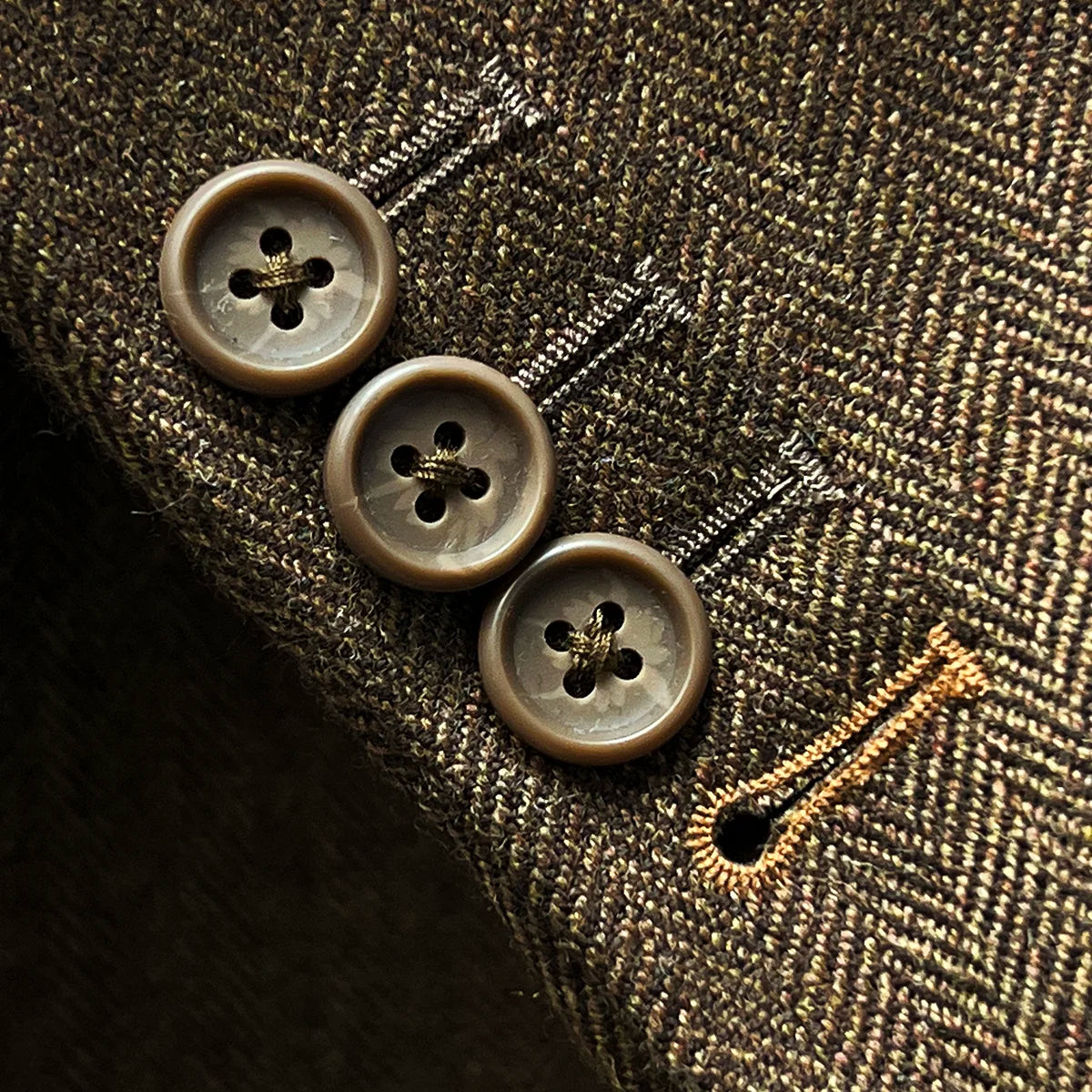 Close-up of working sleeve buttons with light brown contrast buttonholes