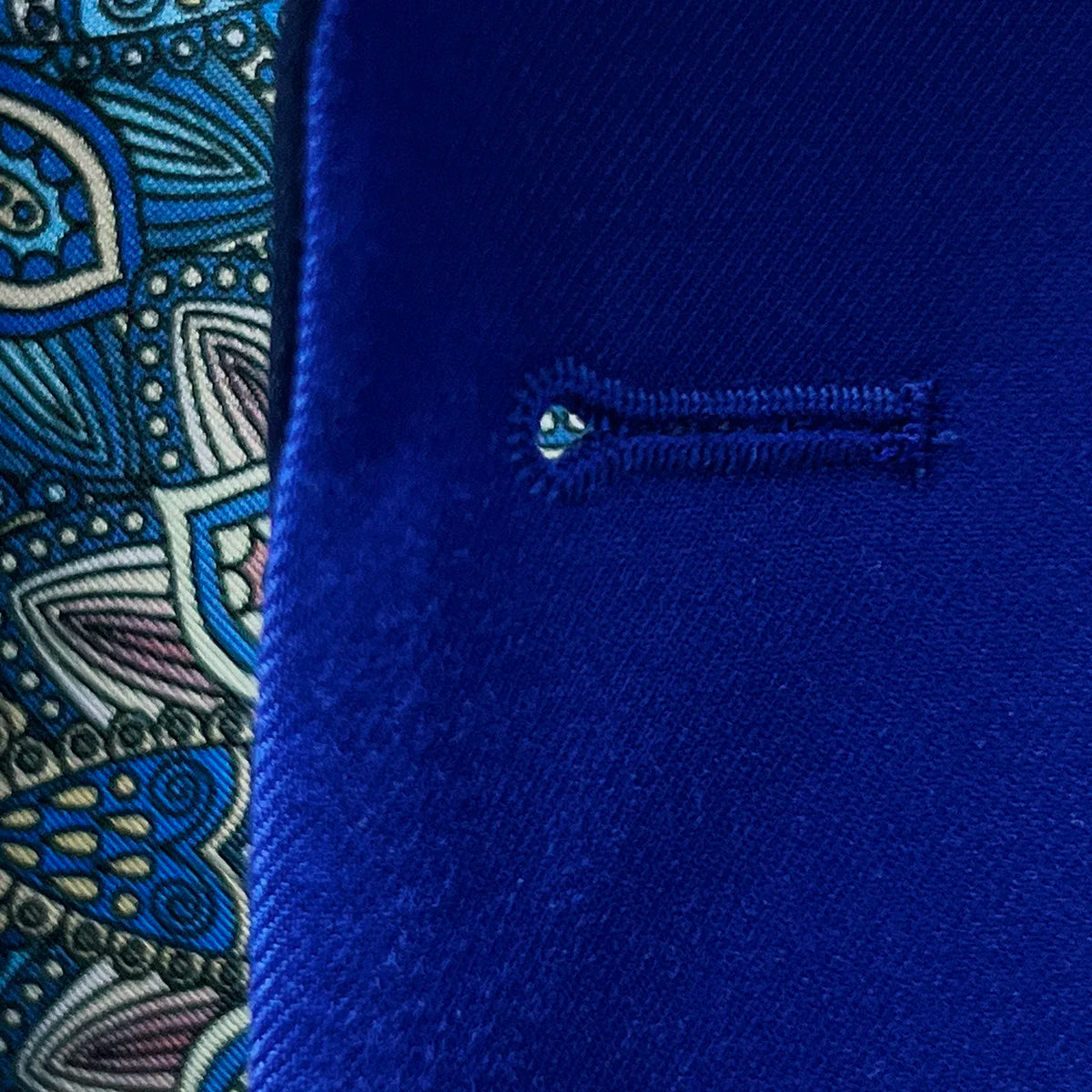 Macro view of precise buttonhole stitching on cobalt blue Super 120s Australian merino wool tuxedo, demonstrating exceptional handwork