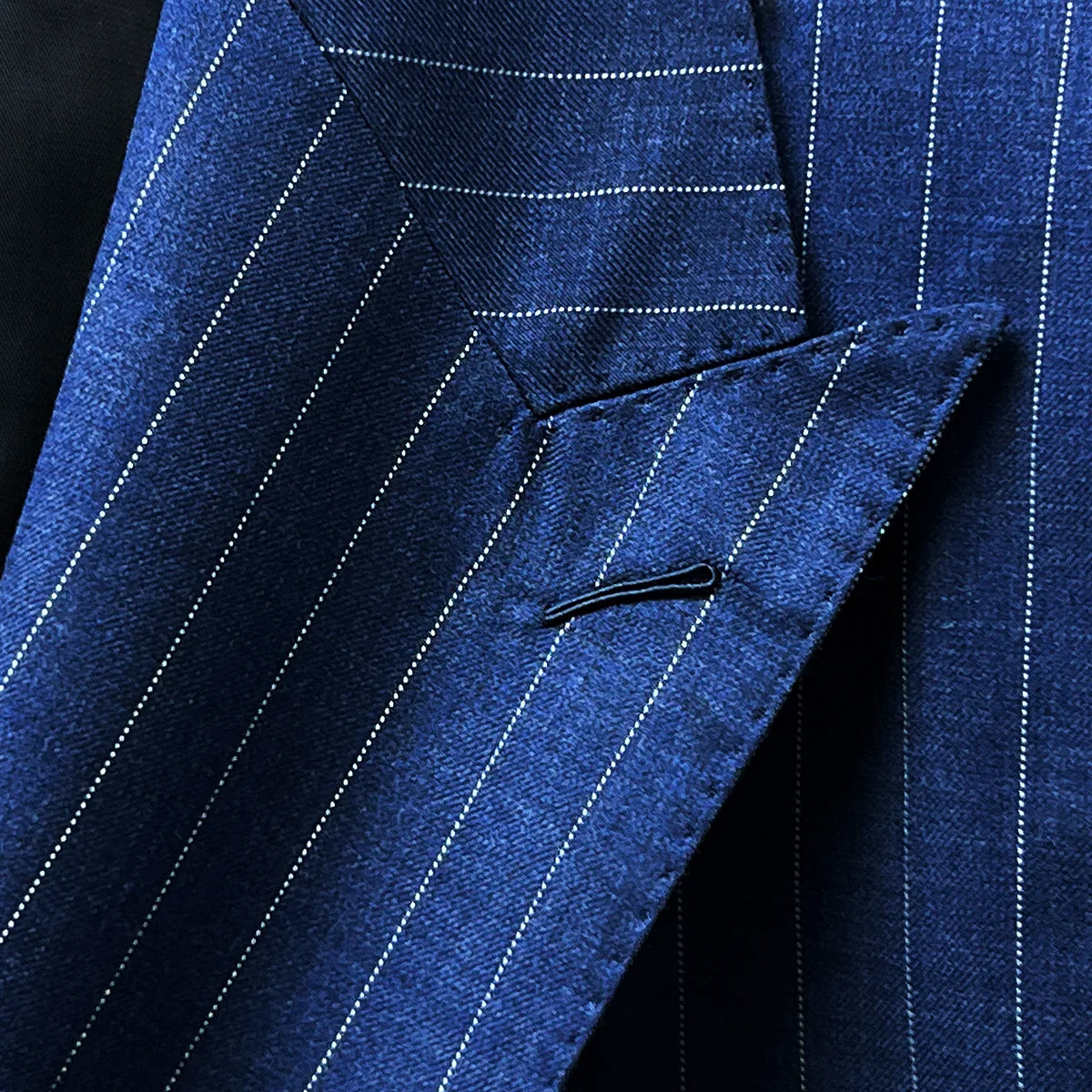 Close-up of the suit's peak lapel, showcasing the sharp angles and fine stitching