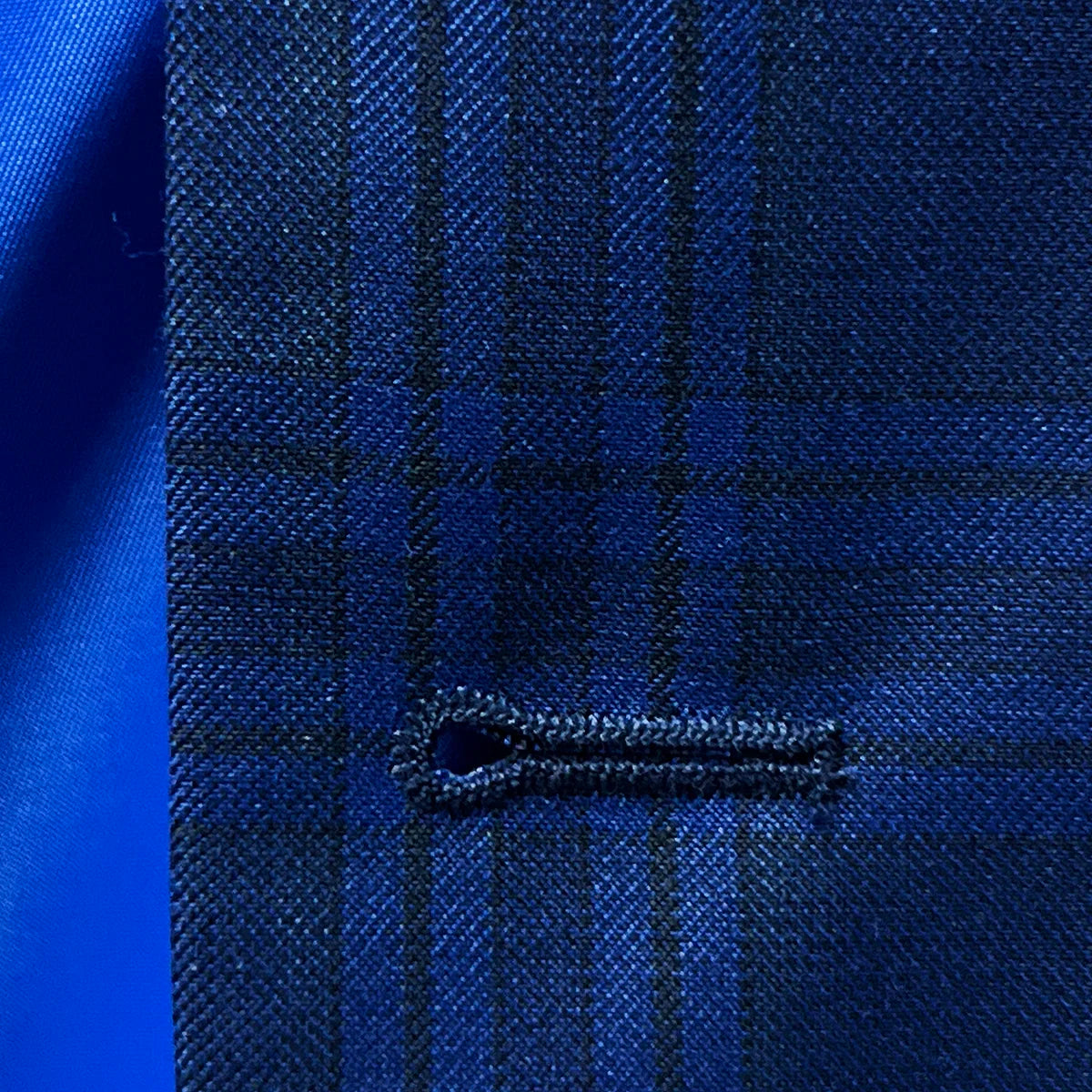 Macro view of precise buttonhole stitching on dark blue Westwood Hart suit