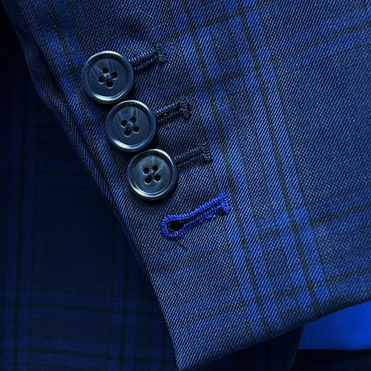 Detail shot of functional buttonholes on suit sleeve, including royal blue accent on last buttonhole