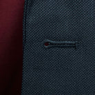 Detailed macro shot of hand-finished buttonhole stitching on dark charcoal grey birdseye suit with deep burgundy contrast thread