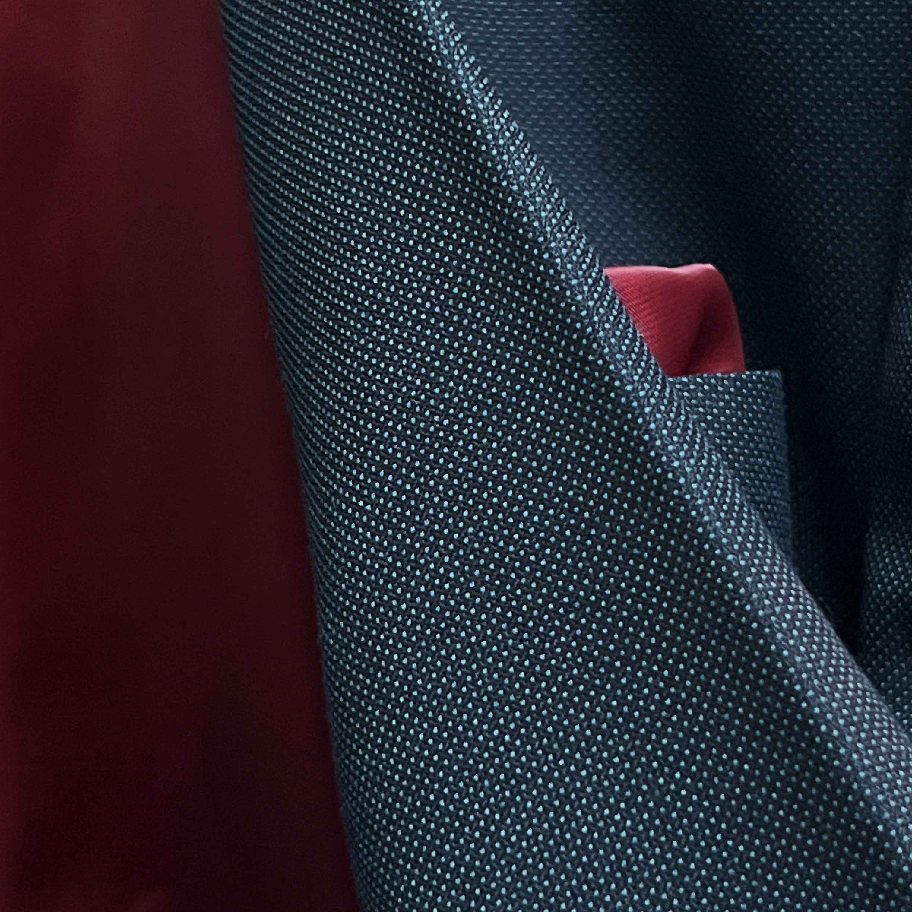 Macro detail shot of birdseye weave texture on dark charcoal grey Super 130s merino wool fabric showing intricate pattern