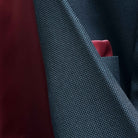 Macro detail shot of birdseye weave texture on dark charcoal grey Super 130s merino wool fabric showing intricate pattern