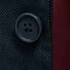Close-up of dark grey horn buttons on dark charcoal grey birdseye suit jacket showing natural marble-like patterns