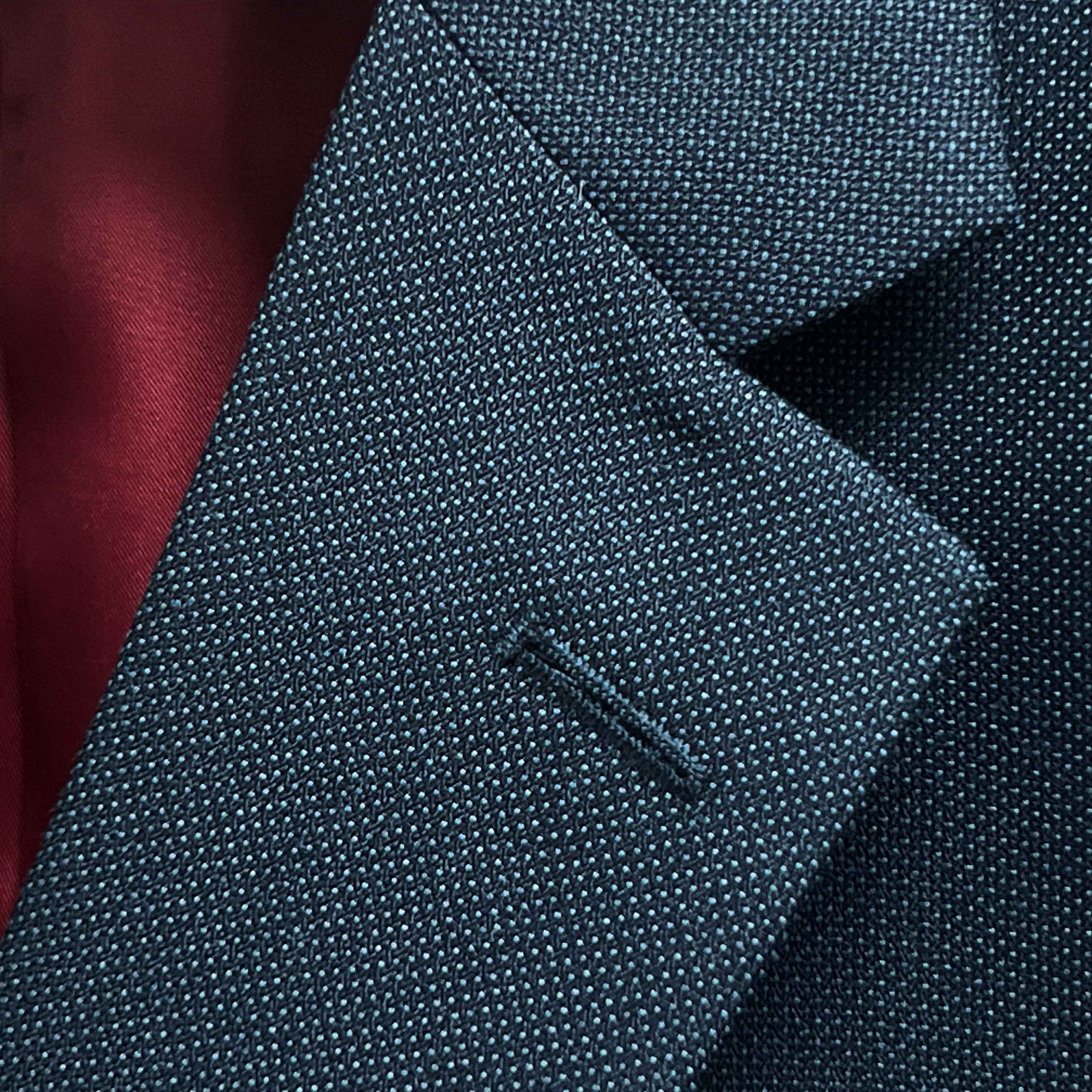 Classic notch lapel detail on dark charcoal grey birdseye suit jacket showing hand pick stitching and textured weave pattern