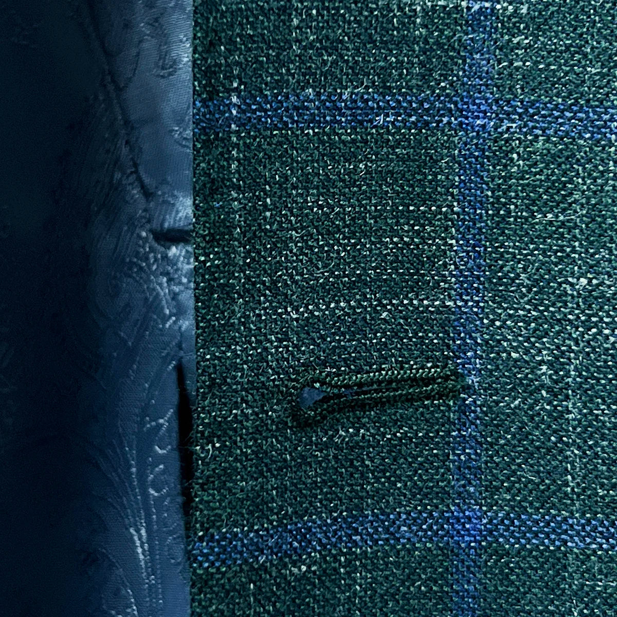 Macro shot of buttonhole stitching on dark green Westwood Hart windowpane sport coat, showcasing precision and craftsmanship