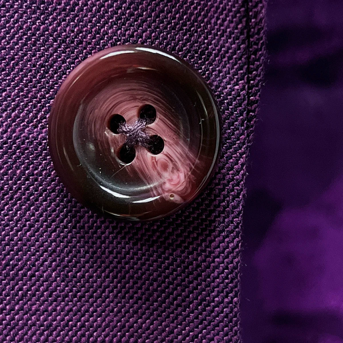 Premium mulberry horn buttons displaying natural marbled texture and rich coloring that complements the purple fabric beautifully