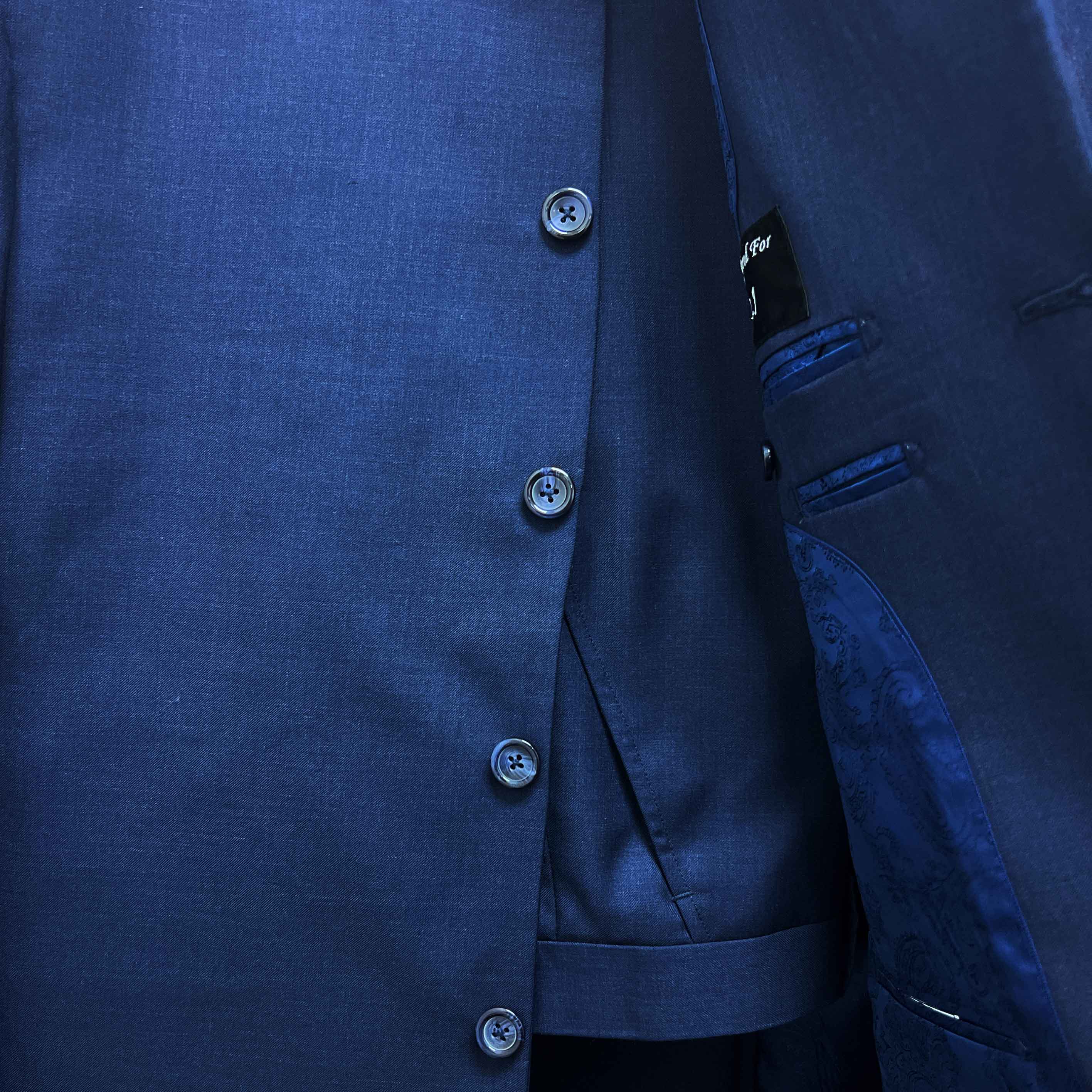 Close-up of a blue suit jacket with buttons and a brand label.
