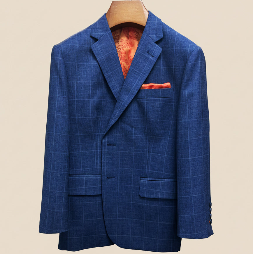 Close-up view of deep blue windowpane check suit jacket showing contrast orange accent buttonhole with hand-finished stitching detail