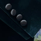 Four black buttons on a dark fabric surface