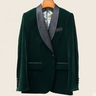 Green velvet tuxedo jacket with gray lapels on a beige background