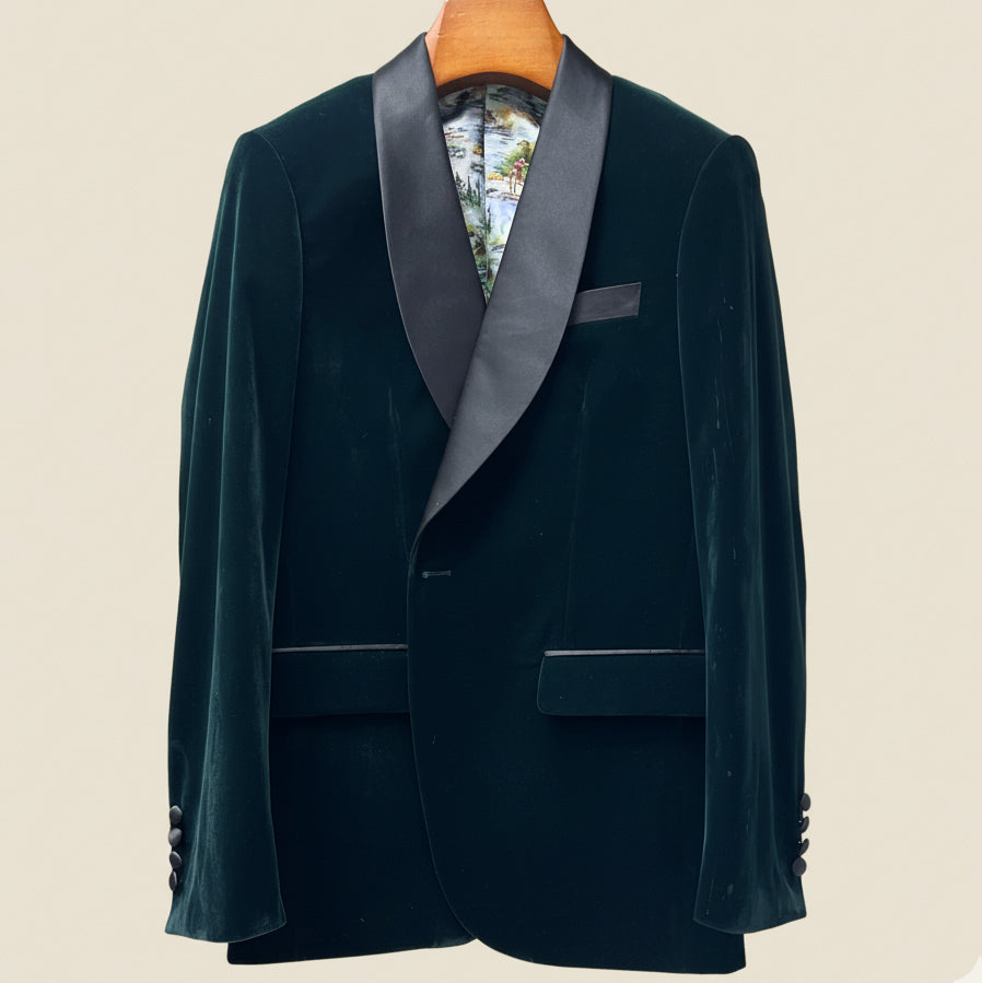 Dark green velvet tuxedo jacket with satin lapels on a beige background