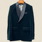 Dark green velvet tuxedo jacket with satin lapels on a beige background