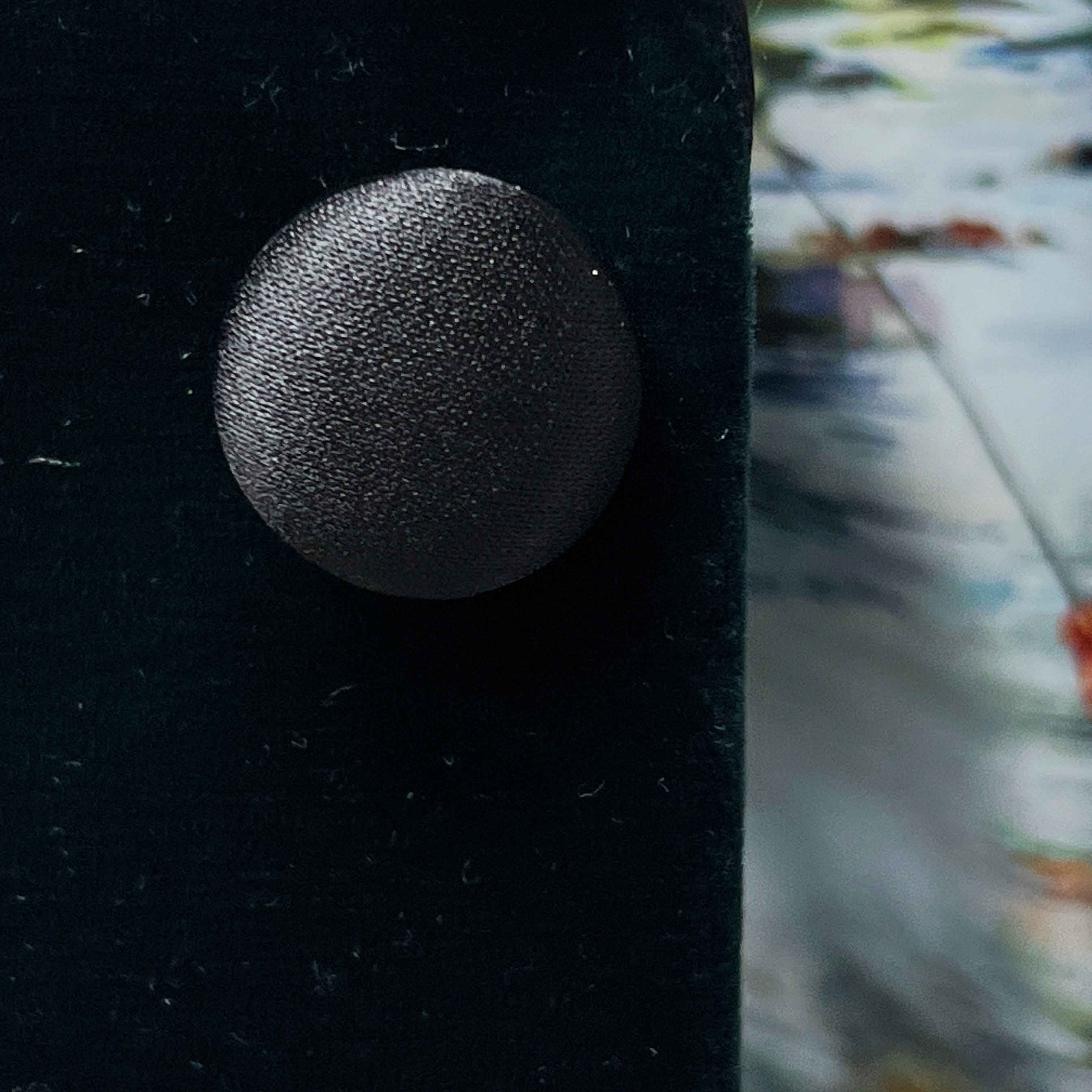 Close-up of a textured black button on a dark fabric background