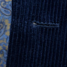 Detailed macro shot of hand-finished buttonhole stitching on deep navy blue corduroy sport coat with light blue contrast thread