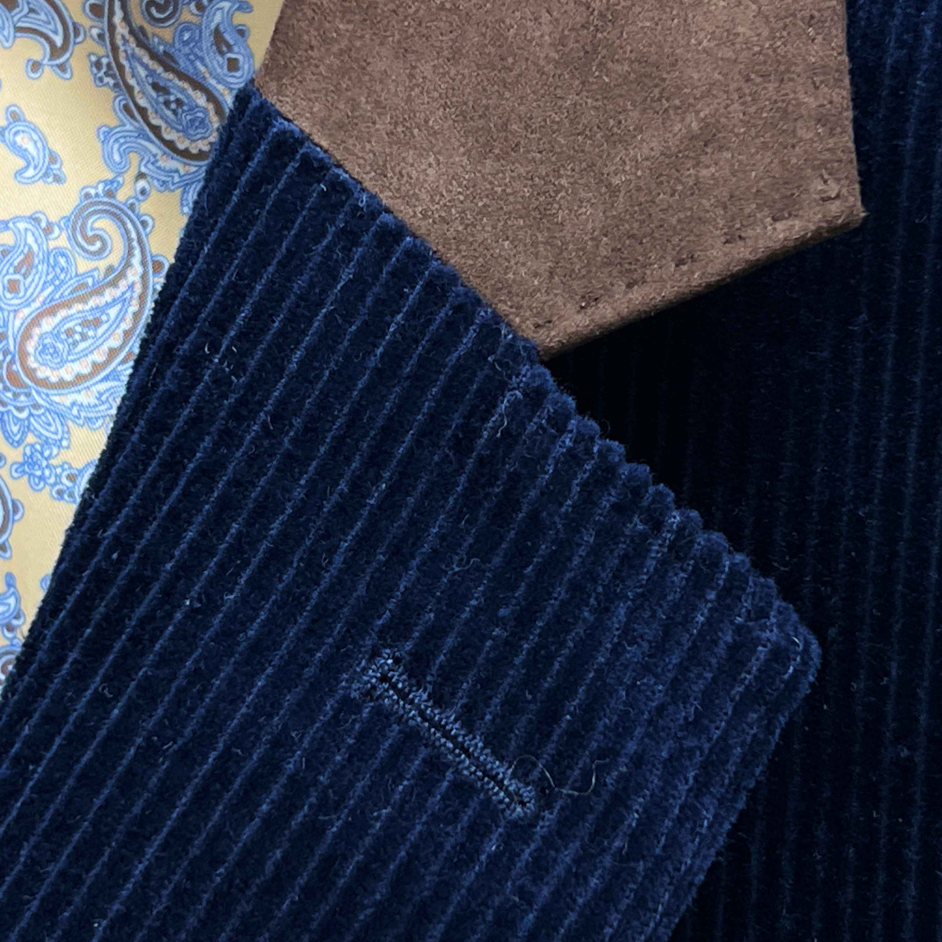 Classic notch lapel detail on deep navy blue corduroy sport coat showing hand pick stitching and brown suede collar