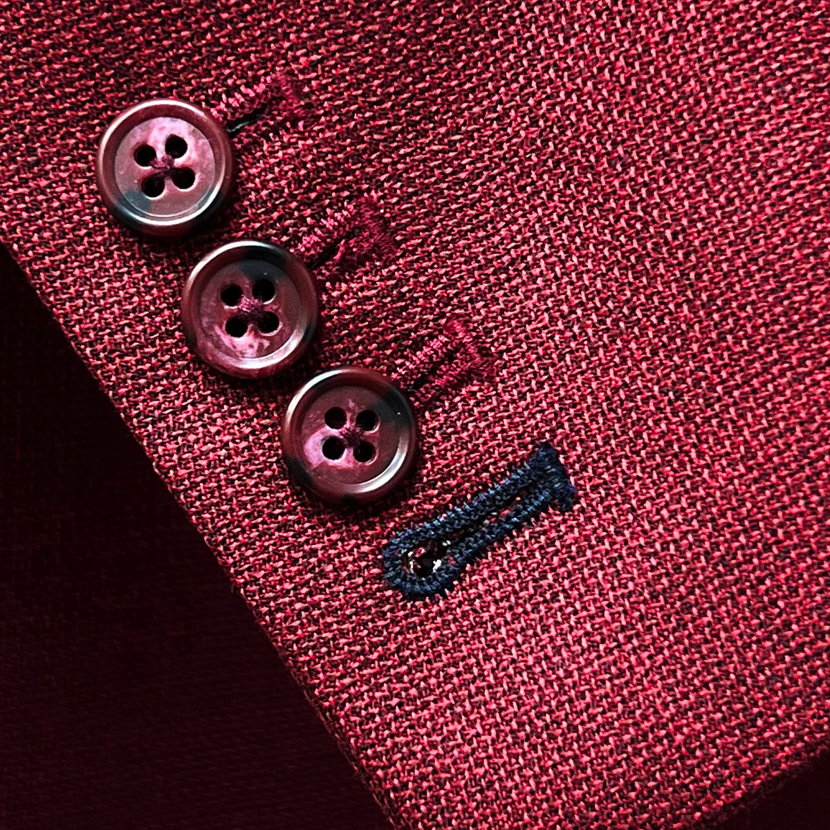 Sport coat jacket sleeve cuff showing functional buttonholes with contrast navy blue accent stitching on deep red basketweave fabric