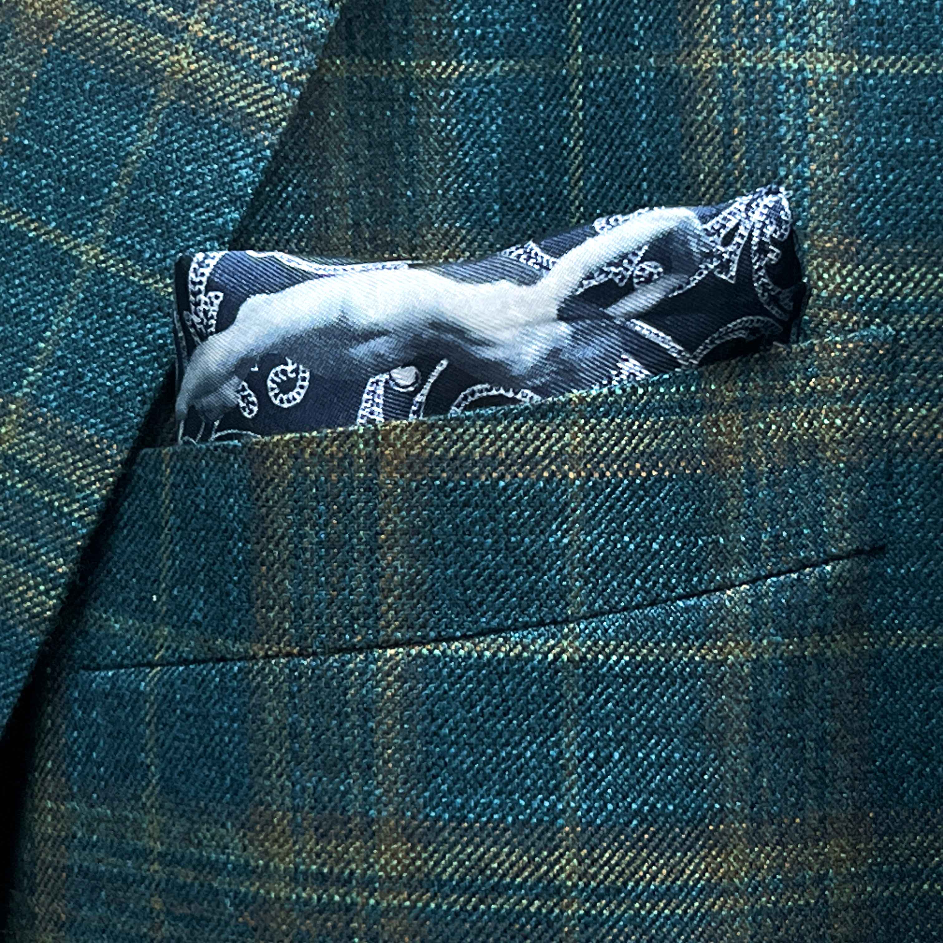 Breast pocket of deep teal green multi check suit jacket with built-in pocket square holder and hand-finished edges