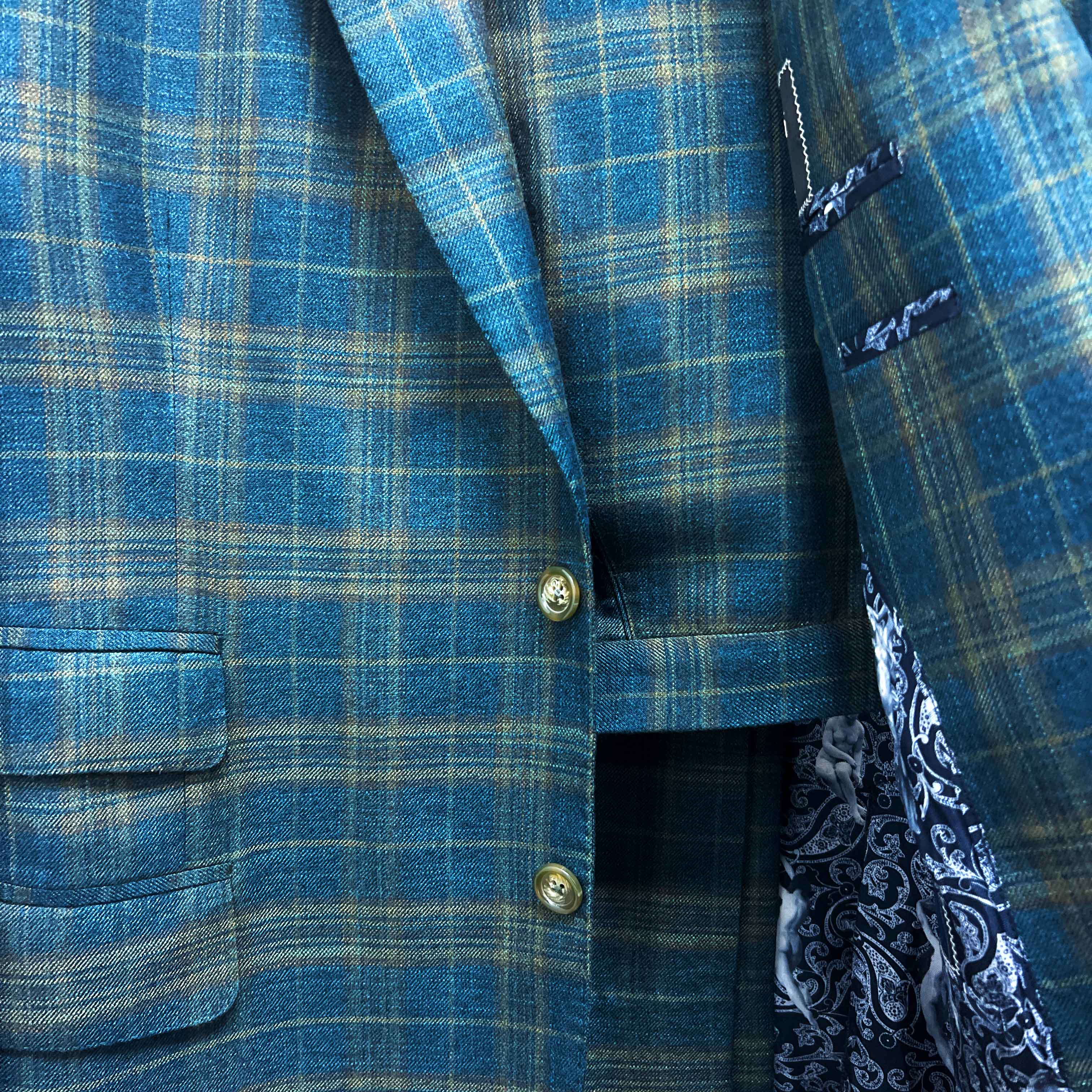 Complete two-piece deep teal green multi check custom suit displayed on hanger showing jacket and trousers with plaid check pattern