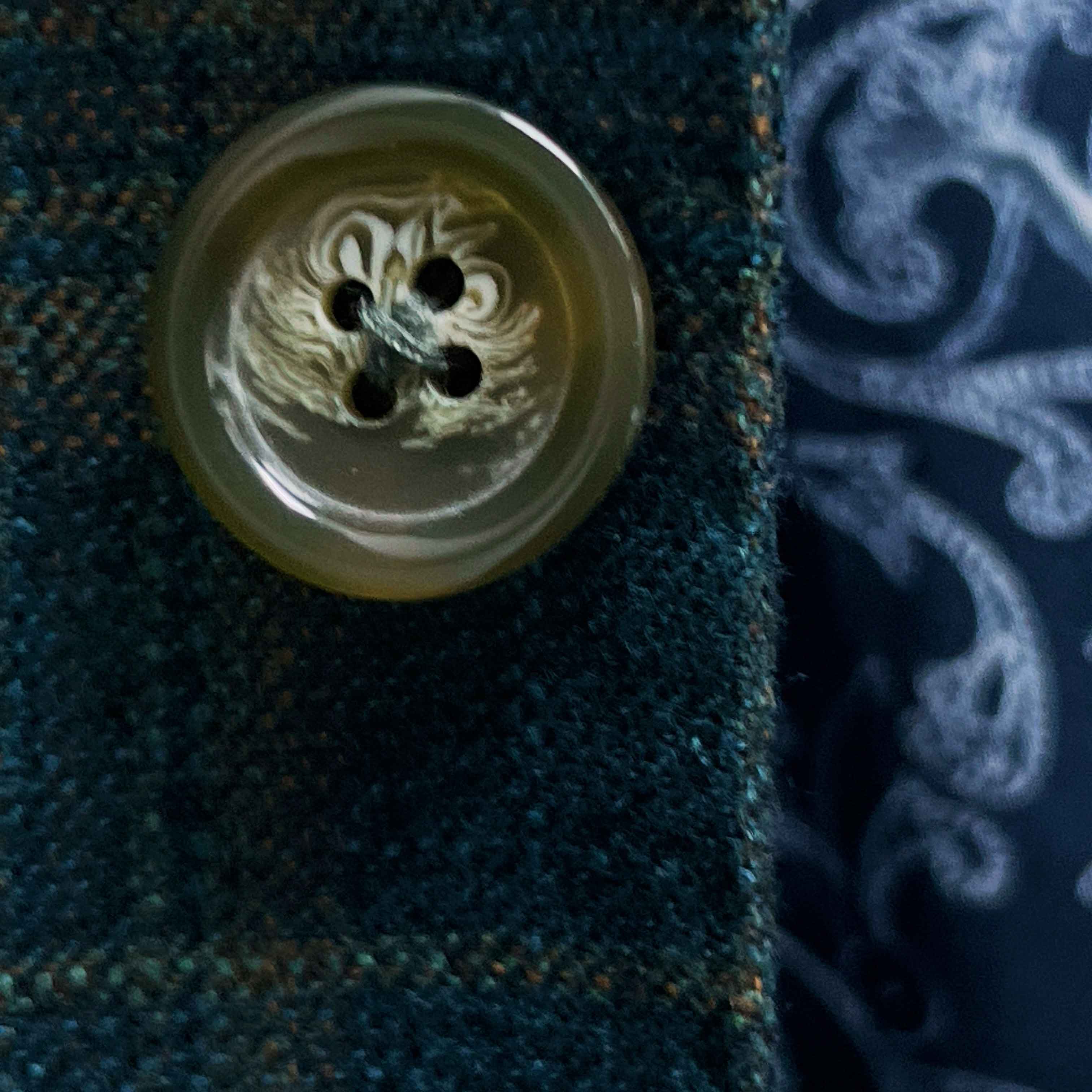 Close-up of olive green horn buttons on deep teal green multi check suit jacket showing natural marble-like patterns
