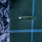Detailed macro shot of hand-finished buttonhole stitching on forest green windowpane sport coat with bright blue contrast thread