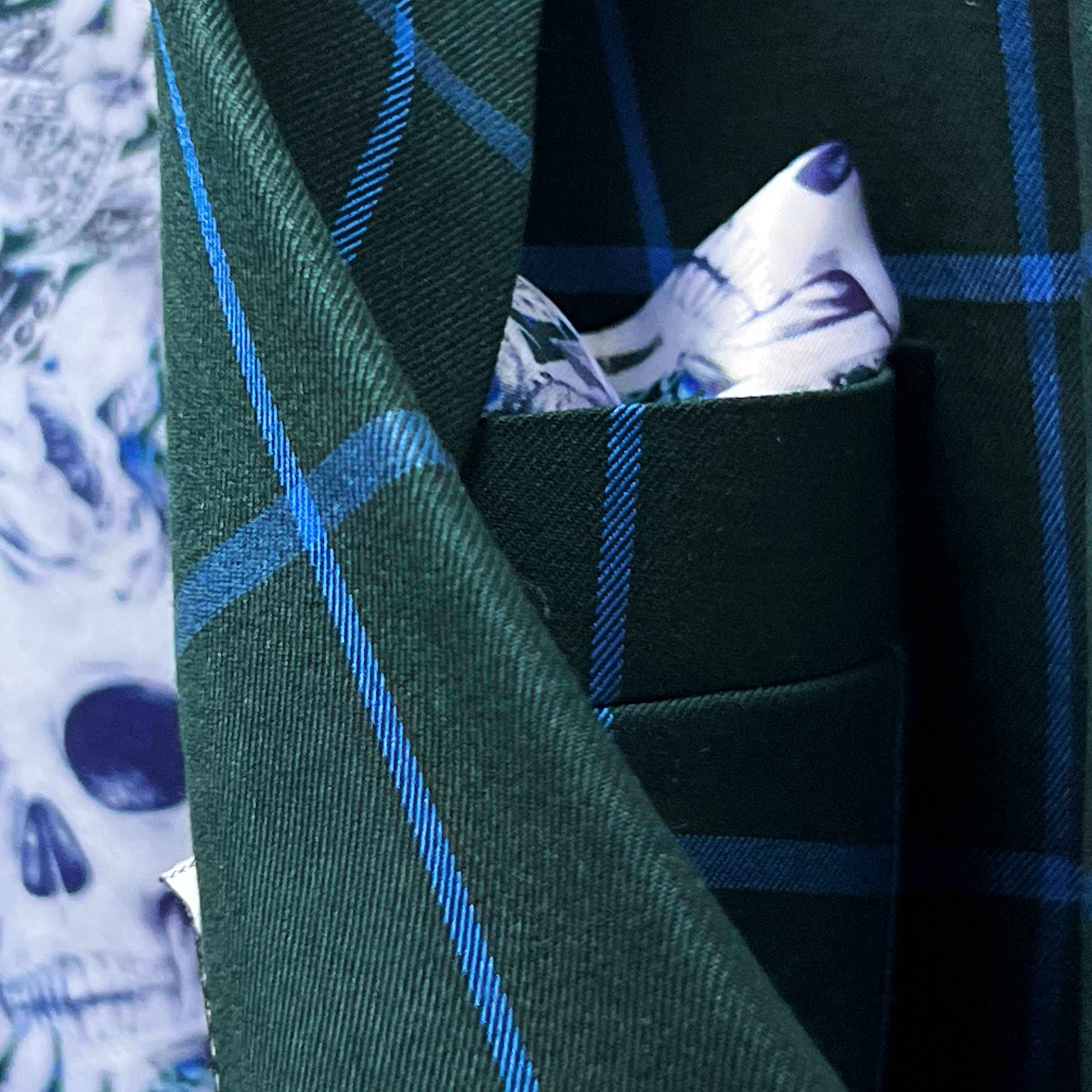 Close-up of Super 130s Australian merino wool fabric showing forest green base with bright blue windowpane check pattern