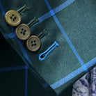 Sport coat sleeve cuff showing functional buttonholes with contrast bright blue accent stitching on forest green windowpane fabric