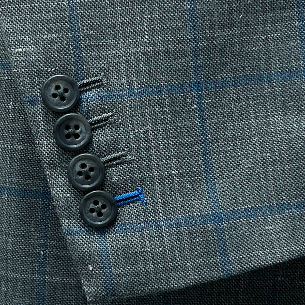 Close-up of the functional sleeve buttonholes on the Westwood Hart grey with medium blue windowpane men's sport coat.
