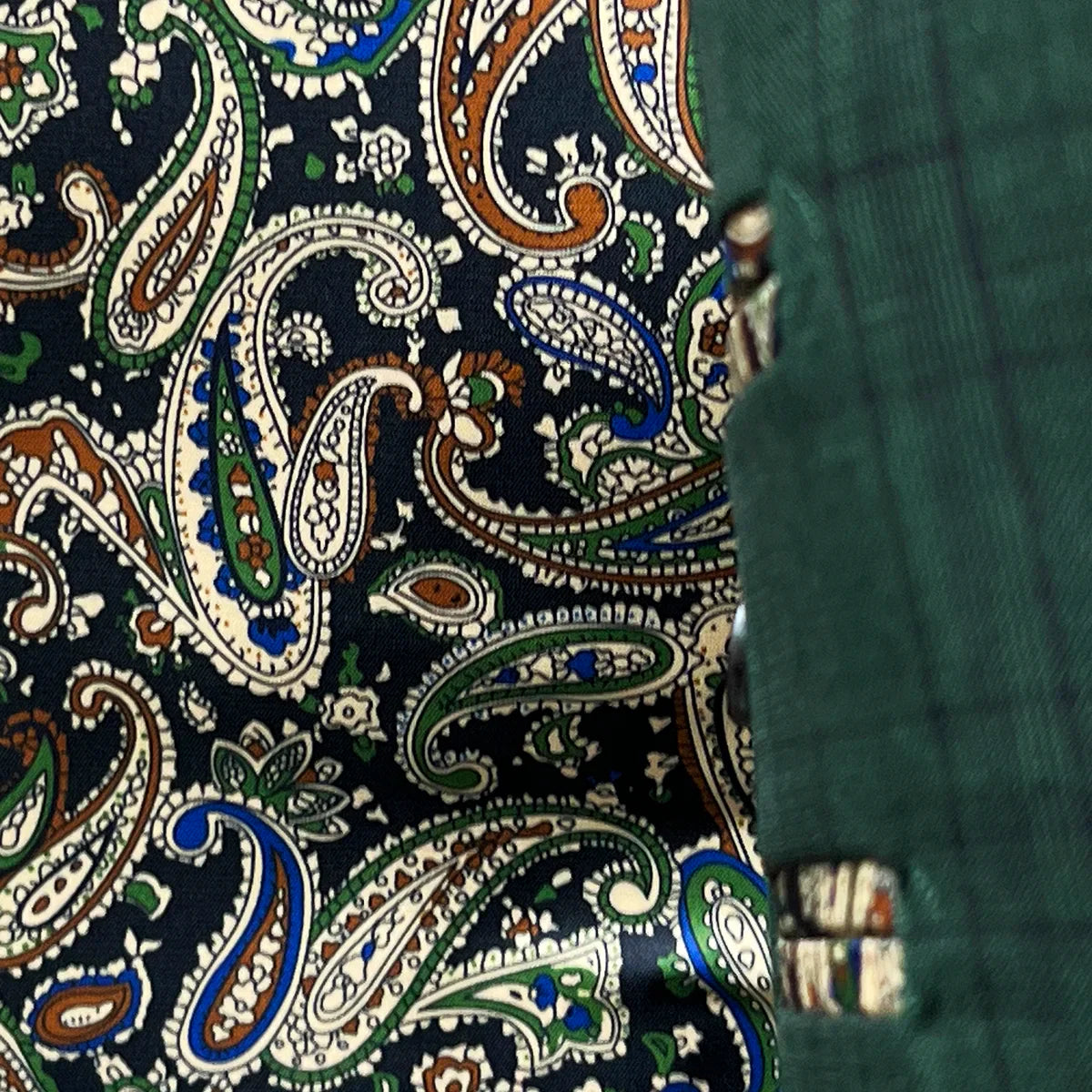 Colorful flash lining detail visible at jacket cuffs and vents in paisley pattern with navy, rust, green and light blue