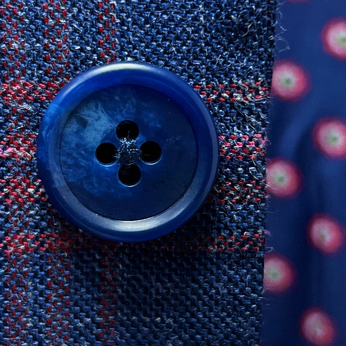 Close-up of navy horn buttons showing natural marbled texture and quality construction against the indigo blue windowpane fabric