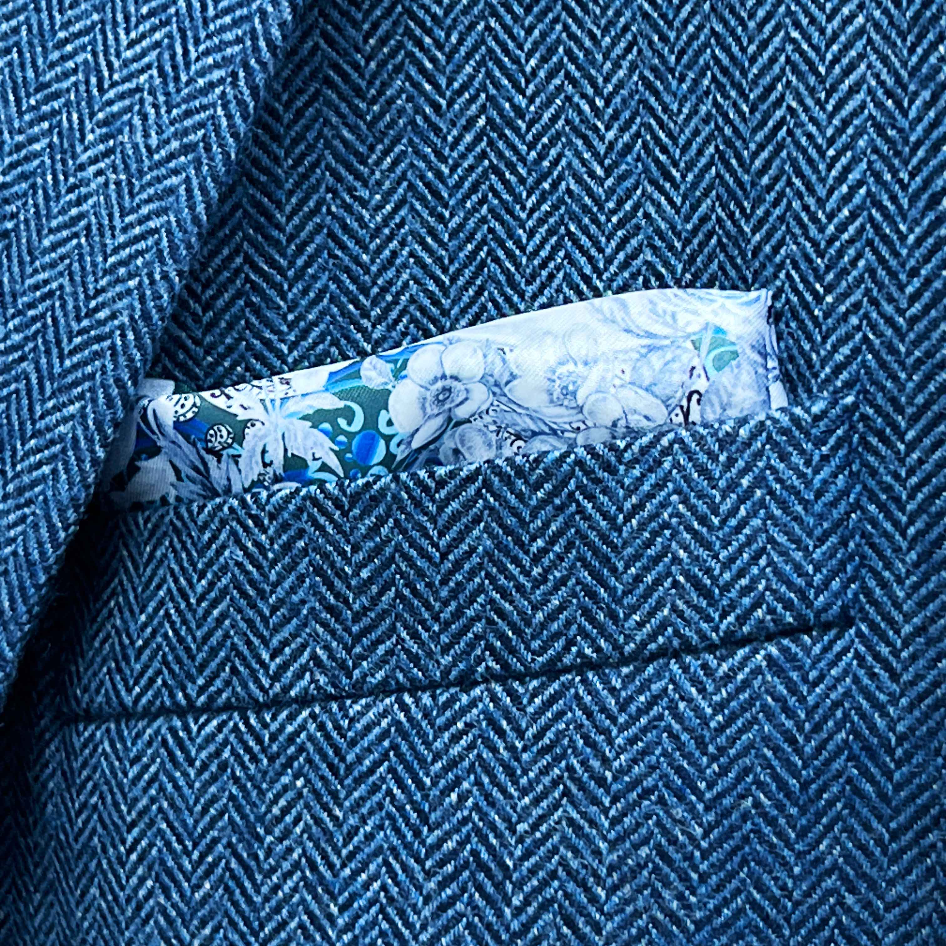Breast pocket of indigo blue herringbone tweed sport coat with built-in floral skull pocket square and hand-finished edges