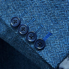 Sport coat sleeve cuff showing functional buttonholes with contrast royal blue accent stitching on indigo blue herringbone tweed fabric