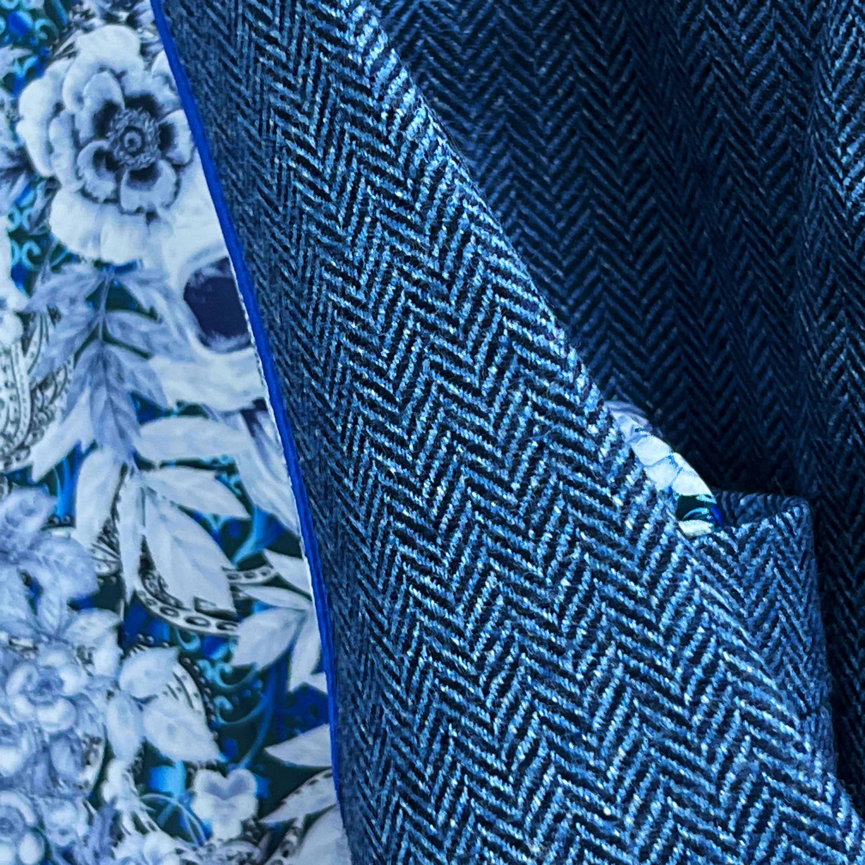 Detailed view of indigo blue herringbone tweed fabric texture showing distinctive diagonal pattern and soft lambswool finish