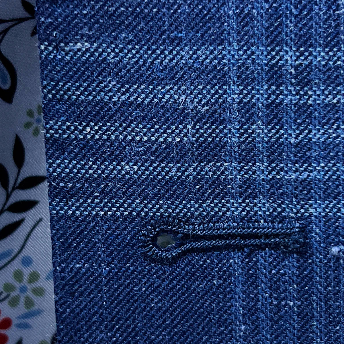 Detailed macro shot of white contrast buttonhole stitching technique showing precision hand-work and thread density on luxury fabric