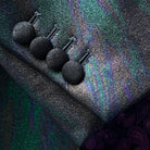 Tuxedo jacket sleeve cuff showing functional buttonholes with black fabric-covered buttons on iridescent colour-shifting fabric