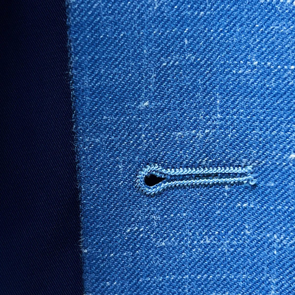 Macro shot of expertly stitched buttonhole on light blue Westwood Hart suit, demonstrating fine tailoring